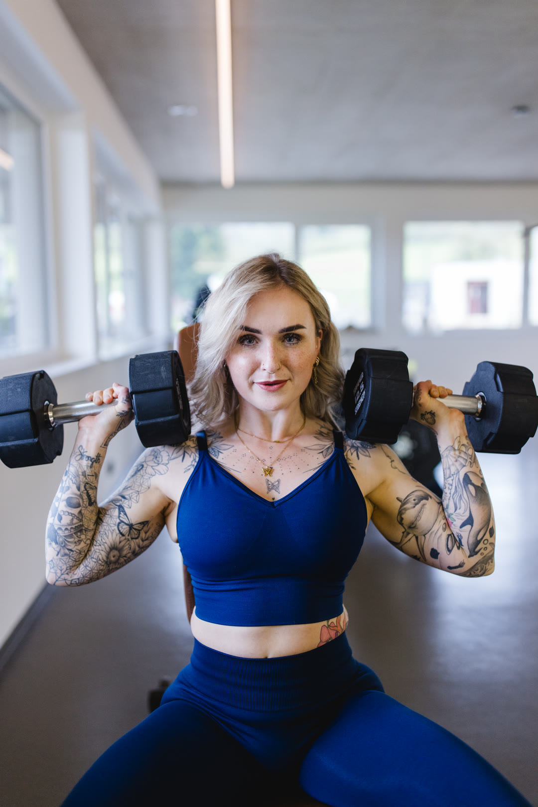 Sarah beim Schulterdrücken mit Kurzhanteln im Gym